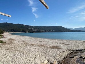 A beach with a clear view of the sea and distant hills.