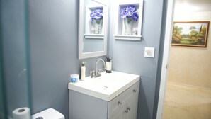 A bathroom with a white sink, mirror, and two shelves with vases.