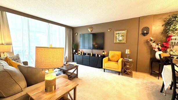 A modern living room with a sofa, a yellow armchair, a coffee table, and a TV mounted on the wall.