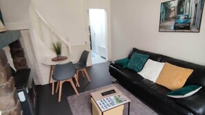 A living room with a black leather sofa, a small table, and a potted plant.