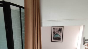 A bedroom with a bed, a window with blinds, and a curtain.