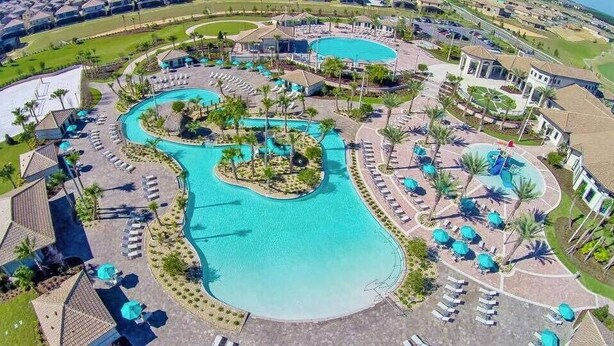 Ein Resort mit mehreren Schwimmbecken, Liegestühlen und Palmen.