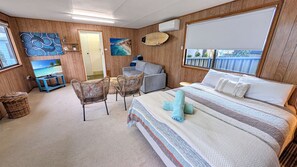 A room with a bed, a television, a chair, a small table, and a window. - Aqua by Experience Jervis Bay (Sanctuary Point)