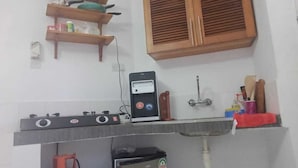 A kitchen with wooden cabinets, a gas stove, a water dispenser, and a gas cylinder. - Lux Suites Royal Palm Studio Apartment (Mtwapa)