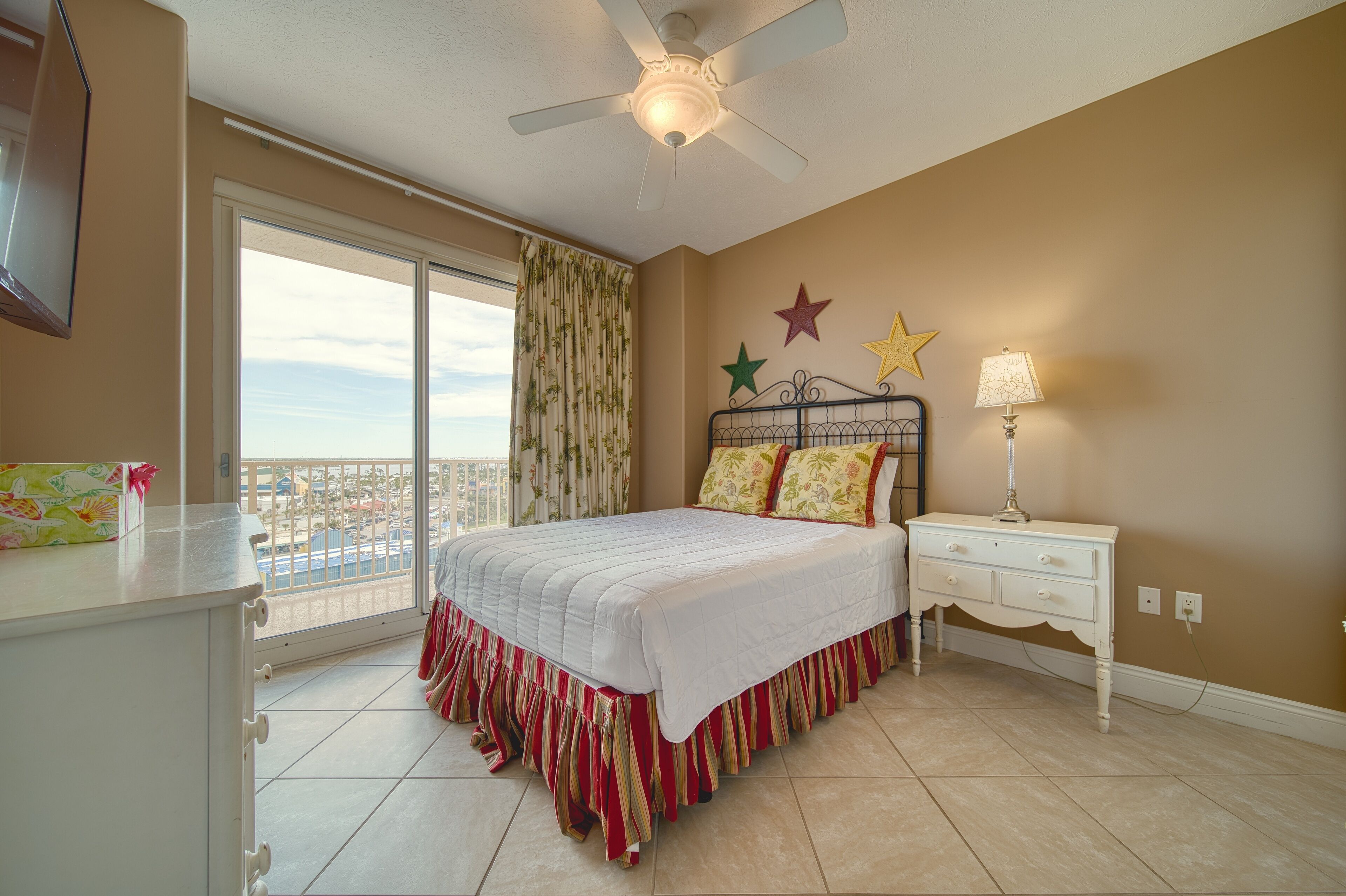 A bedroom with a bed, a nightstand, a ceiling fan, and a window with curtains.
