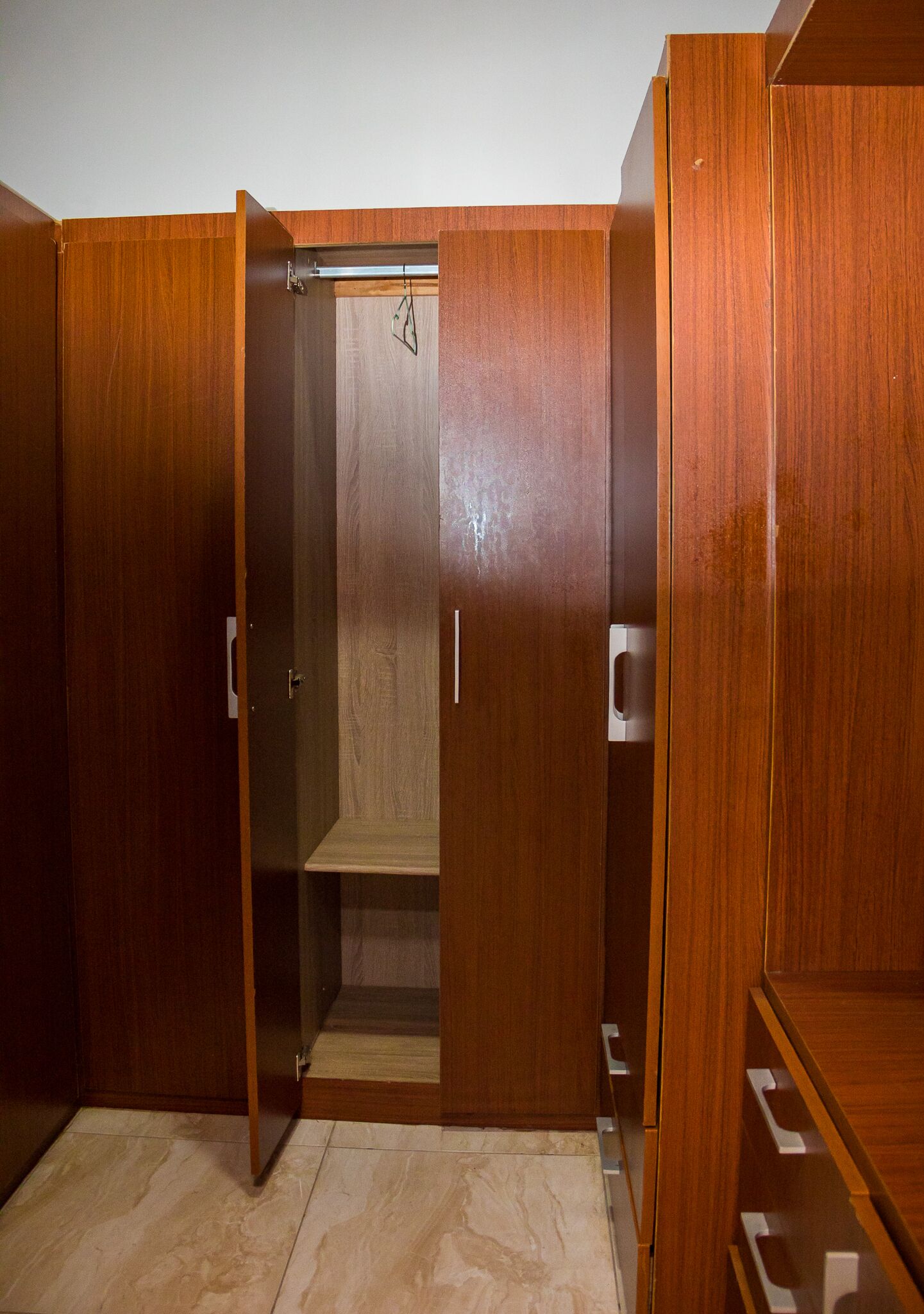 Een houten garderobe met verschillende vakken en een hangstang.