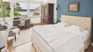 Een slaapkamer met een groot bed, een bureau en uitzicht op een meer.