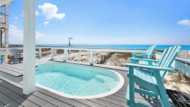 A wooden deck with a hot tub, chairs, and a view of the beach. - Gulf Front Luxury | Private Pool and Elevator (Gulf Shores)