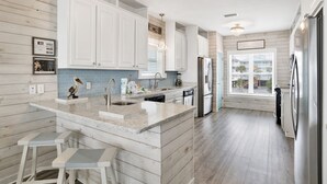 A modern kitchen with white cabinetry, a granite countertop, and stainless steel appliances. - Gulf Front Luxury | Private Pool and Elevator (Gulf Shores)