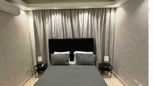 A bedroom with a large bed, two bedside tables, and a headboard. - Burungos Place @ Terrazas Del Caribe D-202 (Santo Domingo Este)