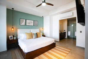 A modern bedroom with a large bed, a ceiling fan, and a bathroom visible through an open door.