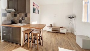 A compact kitchen with a wooden table, stools, and modern cabinetry.