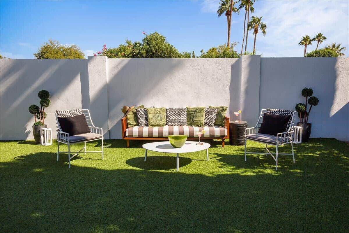 An outdoor seating area with a sofa, two chairs, and a round table.