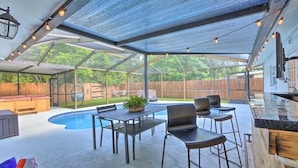 A covered outdoor patio with a pool, bar area, and seating. - SunRay Stay ~ Heated Pool, Putting Green, & Patio (Safety Harbor)