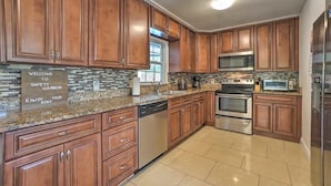 A modern kitchen with wooden cabinets, stainless steel appliances, and a welcome sign. - SunRay Stay ~ Heated Pool, Putting Green, & Patio (Safety Harbor)