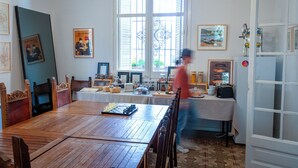 Zona pranzo con tavolo in legno apparecchiato per un pasto, una scacchiera e una persona che passa.
