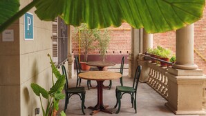 Un'area patio con tavolo e sedie, piante in vaso e un muro in mattoni sullo sfondo.