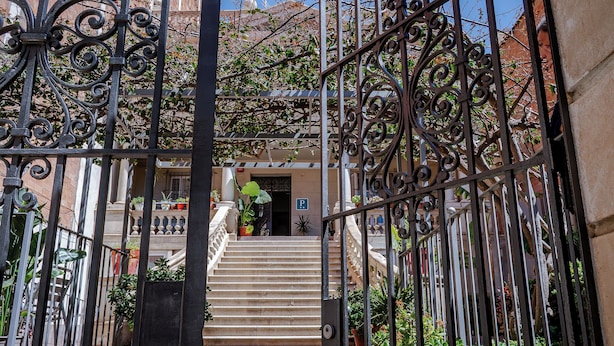 Un cancello in ferro battuto che dà accesso a una scala con vista su un edificio e una porta con la lettera P.