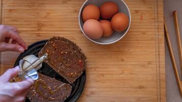 A wooden cutting board with a bowl of eggs and a loaf of bread.