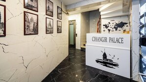 En entréhall med ett marmorgolv, inramade svartvita fotografier på väggarna och en skylt med texten ”CHANGIR PALACE”.