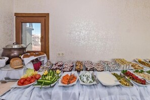 A buffet table with various food items and a pot on the left.