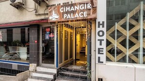Cihangir Palace Hotels exteriör, med en tydligt synlig entré, trappsteg som leder upp till dörren och en skylt som visar hotellets namn.