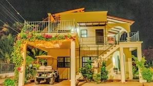 Une maison à deux étages avec un balcon, un escalier et un véhicule garé.