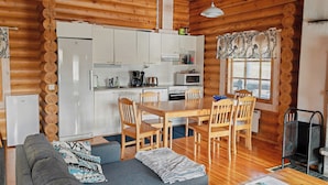 Un intérieur chaleureux de chalet en bois, comprenant un coin repas, une cuisine et un espace de vie.