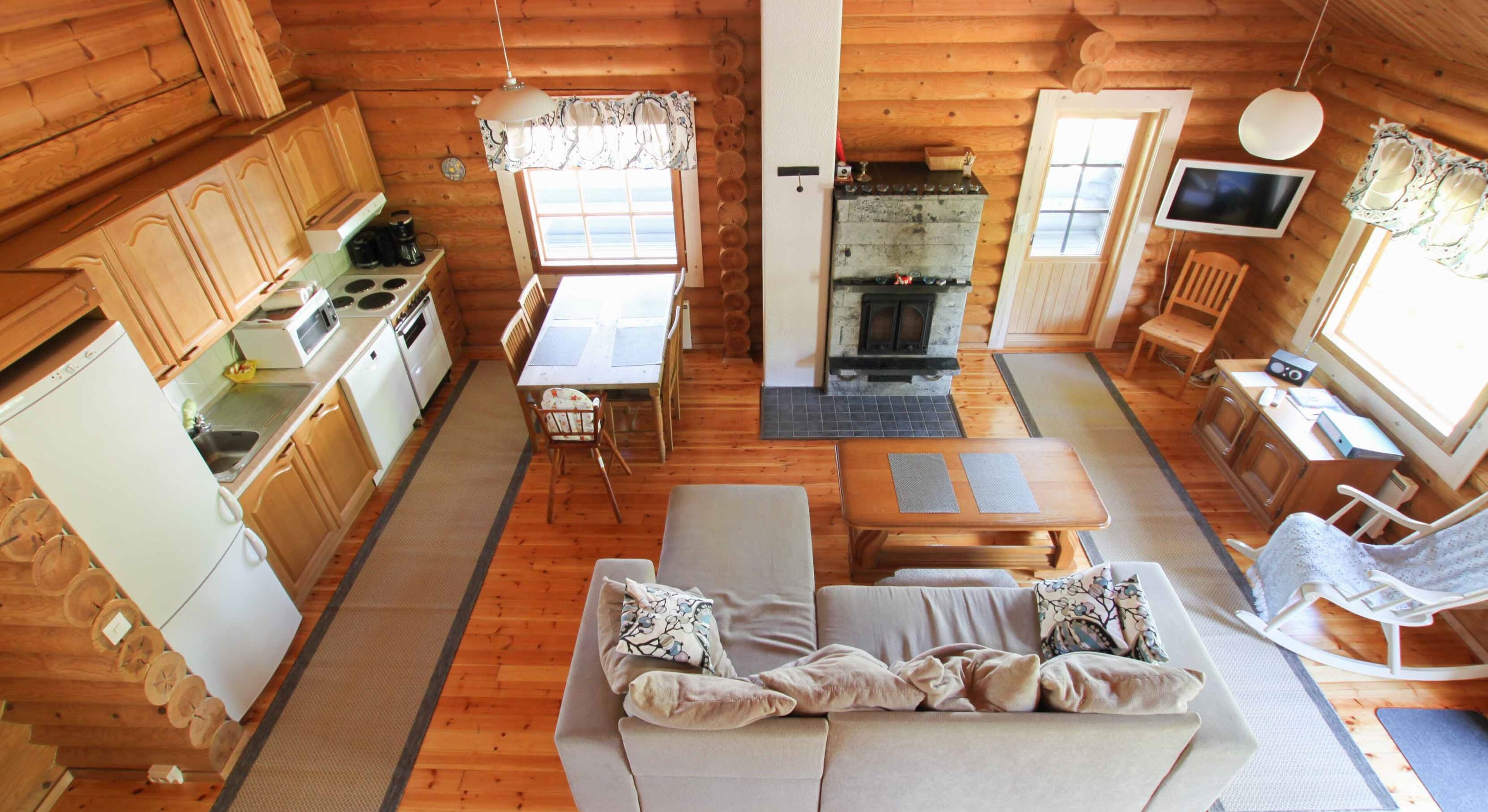 A cozy cabin interior with a dining area, sofa, and a fireplace.