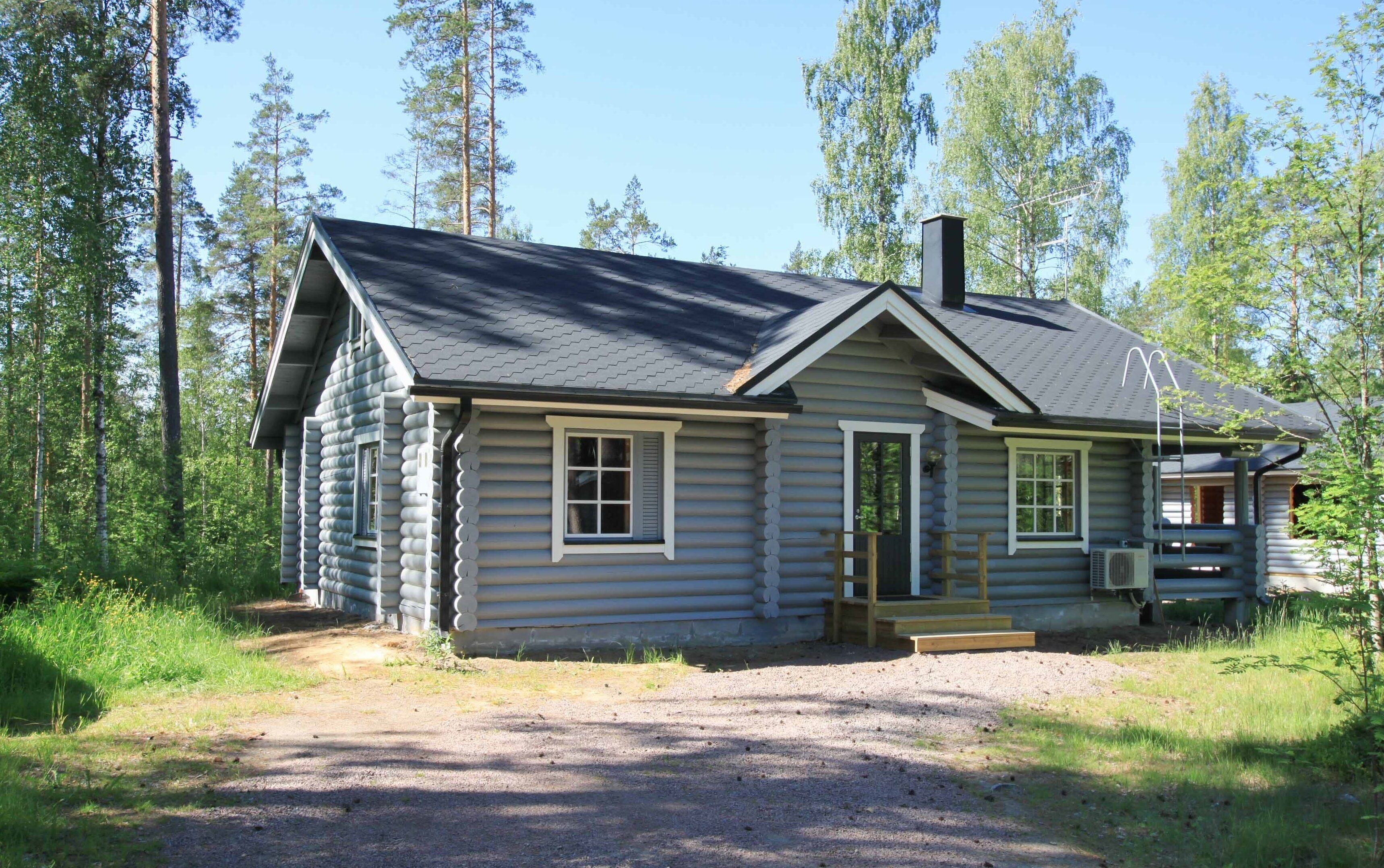 Eine Blockhütte mit Schornstein, einer Veranda und einem Schotterweg.