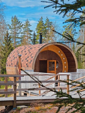 A wooden cabin with a curved roof, a chimney, and a door with circular windows. - Matikkala Cottages (Ruokolahti)
