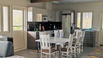 A modern kitchen with white cabinets, a dining table with chairs, and a sofa.