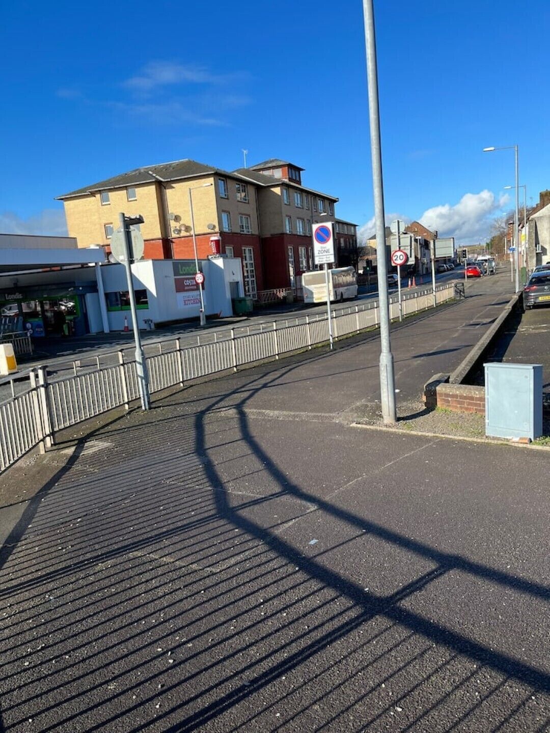 Una strada con una zona pedonale, un cartello dei limiti di velocità e un edificio con un'insegna che dice "Londis".