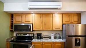 A kitchen with wooden cabinets, a stainless steel refrigerator, a microwave, a stove, and a coffee maker.