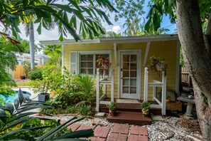 A small yellow house with a porch, surrounded by lush greenery and a swimming pool. - Family Home Heated Pool Victoria Park2BR (Fort Lauderdale)