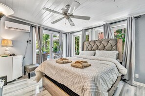 A bedroom with a bed, a ceiling fan, a bedside table, a lamp, and a view of the outdoors. - Family Home Heated Pool Victoria Park2BR (Fort Lauderdale)