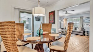 Un coin repas avec une table ronde en bois, des chaises en osier et un luminaire suspendu.