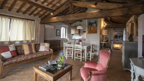 Un salon rustique avec un plafond en bois, un canapé, une table à manger avec des chaises et un fauteuil rouge.