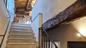 Un escalier avec des marches en pierre et un plafond en bois, menant à l’étage supérieur.