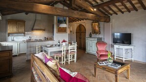 Un vaste espace de vie doté d’un plafond en bois, d’une table à manger avec des chaises, d’un canapé et d’un téléviseur.