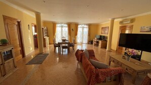 A spacious living room with a sofa, a TV, and a dining area with a table and chairs. - Casa Sabine, beautiful, modern, rural villa with 10m x 5m private pool (Zurgena)