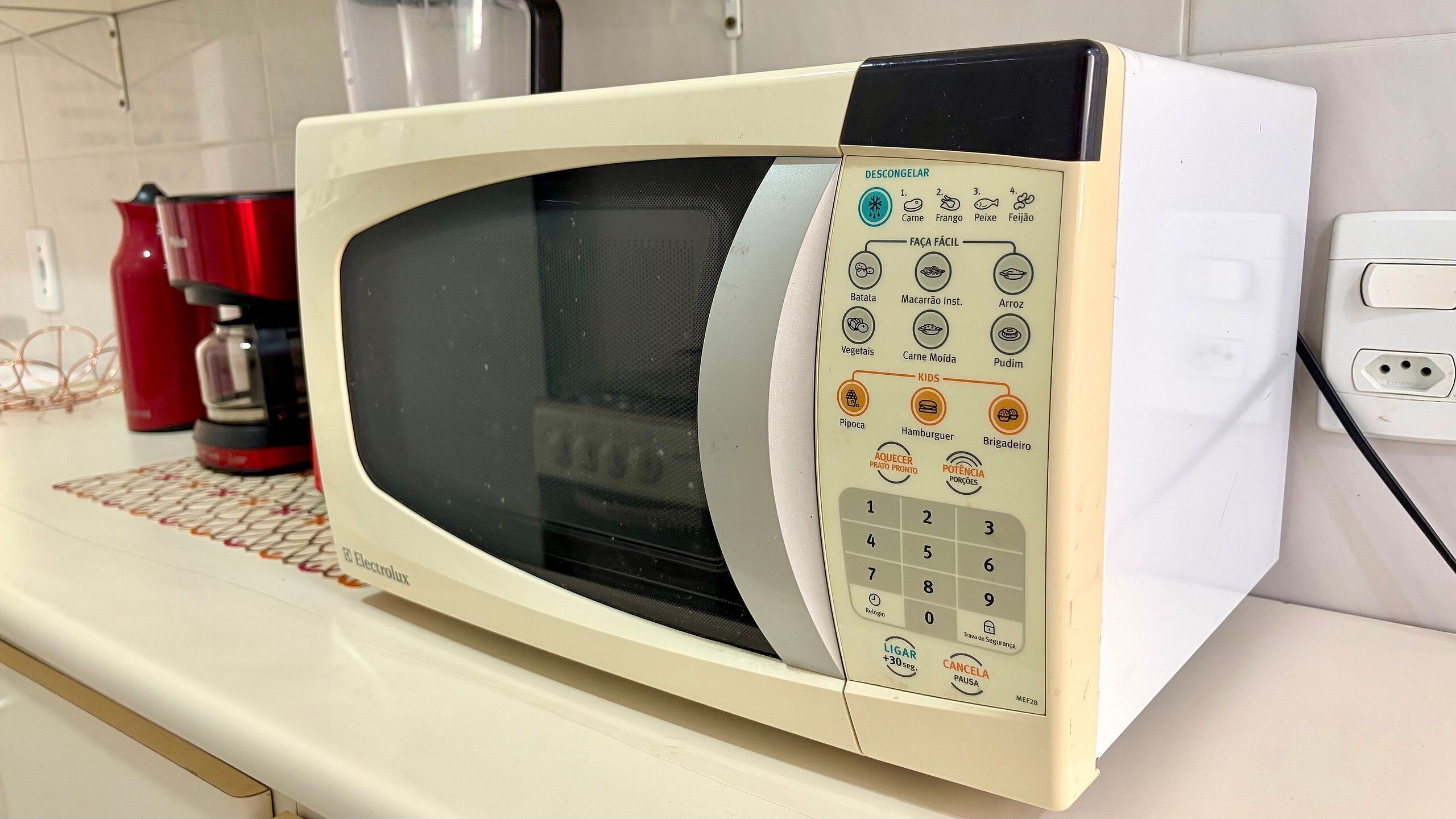 Um forno de micro-ondas branco com painel de controle e diversas funções de cozimento e um temporizador.