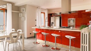 Une cuisine moderne avec des meubles rouges, un îlot central doté de tabourets de bar et une vue sur l’extérieur.