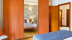 Une chambre à coucher avec un lit, une armoire en bois, un mur en pierre et un plancher en bois.