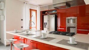 Une cuisine moderne dotée d’un îlot central, d’appareils électroménagers en acier inoxydable et de meubles de rangement rouges.