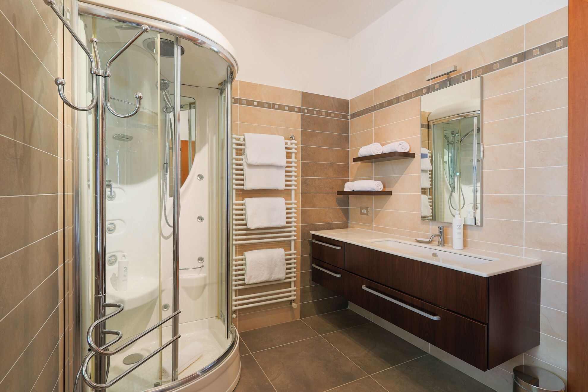 A modern bathroom with a glass-enclosed shower, a vanity with a mirror, and a towel rack.