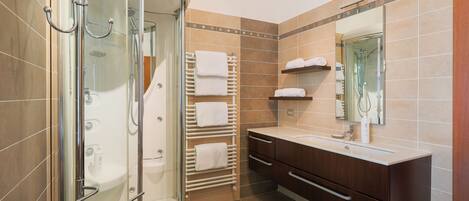 A modern bathroom with a glass-enclosed shower, a vanity with a mirror, and a towel rack.