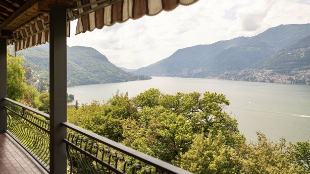 Un balcon donnant sur un lac entouré de montagnes.