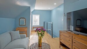 Ein Zimmer mit einer Couch, einem Holzk dresser, einem Spiegel und einer Vase mit Blumen.