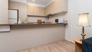 Une cuisine moderne avec des meubles de couleur bois clair, un four à micro-ondes et un petit espace de comptoir.
